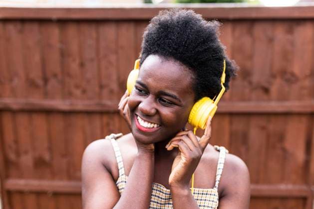 Smiling woman listening to music through headphones in front of wooden wall model released, Symbolfoto, WPEF07830