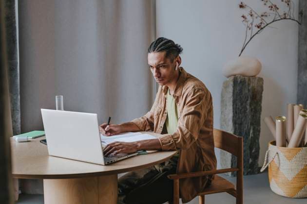 Dedicated young man using laptop learning through online tutorial at home model released, Symbolfoto property released, YTF01494
