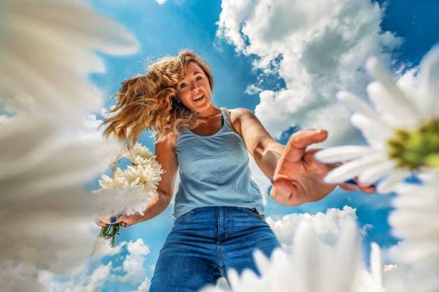 Creative Highlights Symbolbilder Woman picking flowers with blue sky and white clouds behind her Tulsa, Oklahoma, United States CR_KRRY231229-1313859-01 ,model released, Symbolfoto