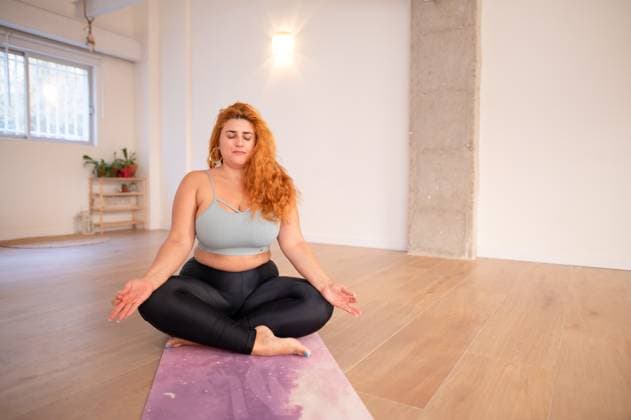 Creative Highlights Symbolbilder Concentrated curvy woman in yoga asana pose in yoga studio Full body of young flexible barefoot plus size lady in sportswear sitting on mat while practicing yoga asana during yoga class against sunlit white wall Model Released MiguelCano_ID18482_551817_040 Copyright: xMiguelxCanox