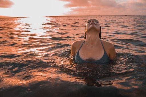 Creative Highlights Symbolbilder A curly brunette female posing in the ocean under the cloudy sunset sky 867453 ,model released, Symbolfoto RECORD DATE NOT STATED
