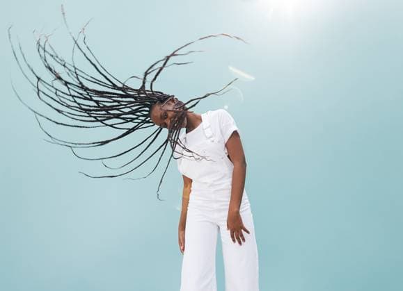 Creative Highlights Symbolbilder Young female waving her long braids while standing outdoors at a blue wall Young female waving her long braids while standing outdoors at a blue wall Copyright: xxArtemxVarnitsinx