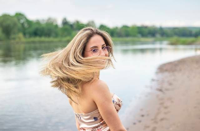 Creative Highlights Symbolbilder glückliche junge Frau mit wehenden Haaren steht am Fluss *** happy young woman with flowing hair stands by the river