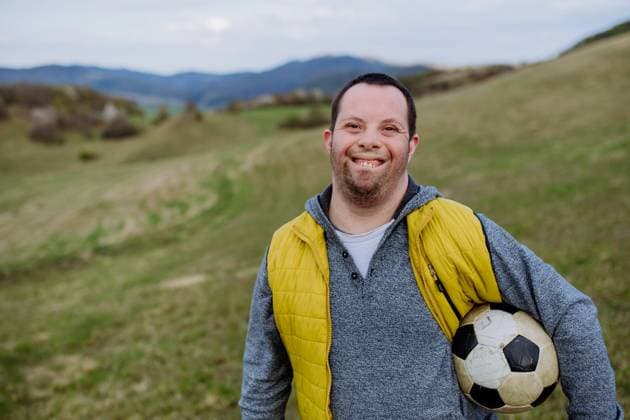 Happy young man with Down syndrome playing with soccer ball in nature. Happy young man with Down syndrome playing with a soccer ball in nature. model released Copyright: xx HHH DAY DOWN SYNDROME BS 2022 HHH 070