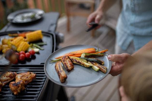 Father putting grilled meat and vegetable on plate to his son during family summer garden party. A father putting grilled meat and vegetable on plate to his son during family summer garden party. model released Copyright: xx HHH FAMILY GRILL BODOVCI 2022 HHH 154