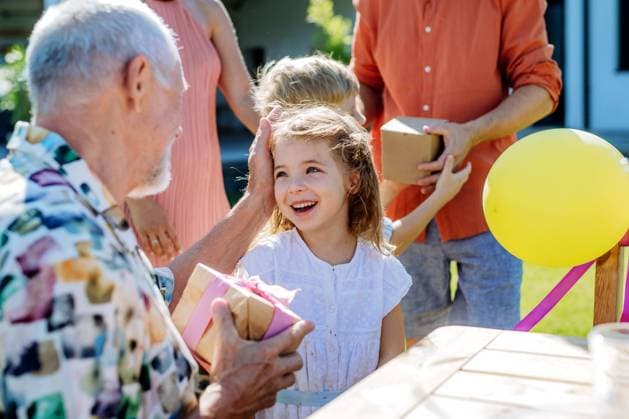 Happy little girl giving birthday present to her senior grandfather at generation family birthday party in summer garden A happy little girl giving birthday present to her senior grandfather at generation family birthday party in summer garden model released Copyright: xx HHH FAMILY POOL PARTY 2022 HHH 207