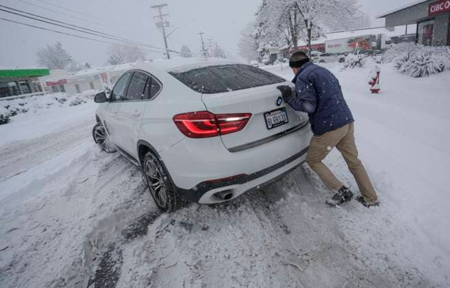 (240117) -- VANCOUVER, Jan. 17, 2024 -- A person tries to push a car trapped in snow in Vancouver, British Columbia, Canada, on Jan. 17, 2024. Environment Canada issued a snowfall warning for the province of British Columbia on Wednesday. The Metro Vancouver region saw up to 20 centimetres of snow, causing schools to close and flights to be delayed and cancelled. (Photo by Xinhua) CANADA-VANCOUVER-HEAVY SNOW LiangxSen 