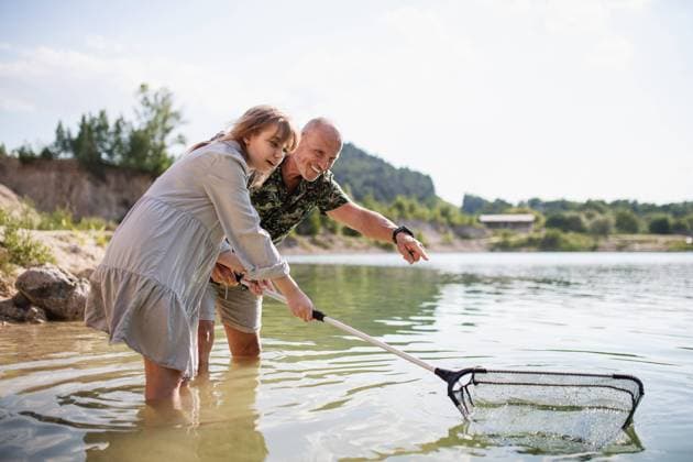 Happy preteen girl and grandfather with fishing net on summer holiday by lake. Happy preteen girl and senior grandfather with fishing net on summer holiday by lake. model released Copyright: xx Family_Lake_Holidays_2021_115