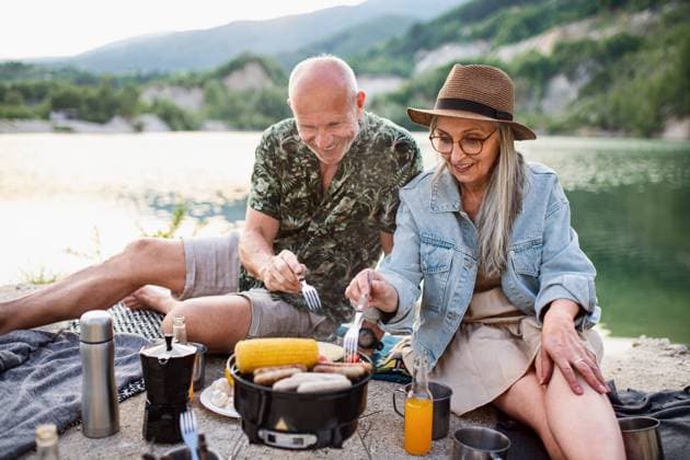 Happy senior couple resting on summer holiday trip, barbecue by lake. Portrait of happy senior couple resting on summer holiday trip, barbecue by lake. model released Copyright: xx Family_Lake_Holidays_2021_280