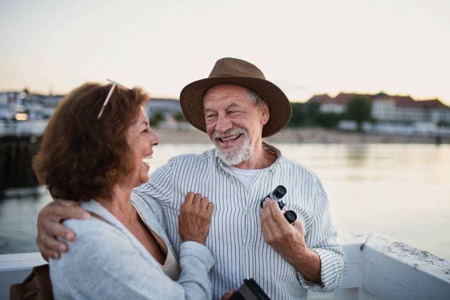 Happy senior couple hugging outdoors on pier by sea, looking at each otherand laughing. Happy senior couple in love hugging outdoors on pier by sea, looking at each otherand laughing. model released Copyright: xx Poland_Senior_Seaside_Pier_2021_042