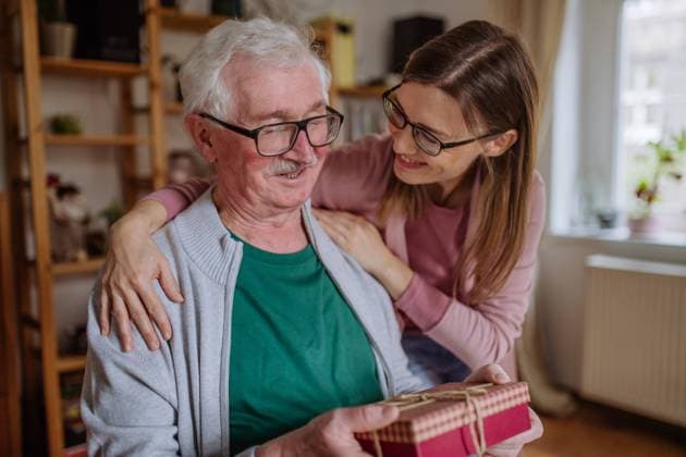 Happy woman surprising her senior father when visiting him at home and bringing present. A happy woman surprising her senior father when visiting him at home and bringing present. model released Copyright: xx Senior_Father_Adult_Daughter_2022_119