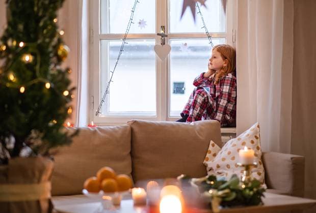 Portrait of small sad girl in pajamas indoors at home at Christmas, sitting on window. Side view of portrait of small sad girl in pajamas indoors at home at Christmas, sitting on window. model released Copyright: xx Christm_Mood_BS_Kids_Wolf_2019_204