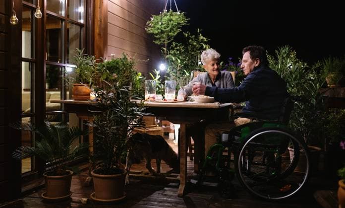 Senior couple in wheelchair having dinner in the evening on terrace, drinking wine. Happy senior couple in wheelchair having dinner in the evening on terrace, drinking wine. model released Copyright: xx Gitka a Tonko Terrace 086