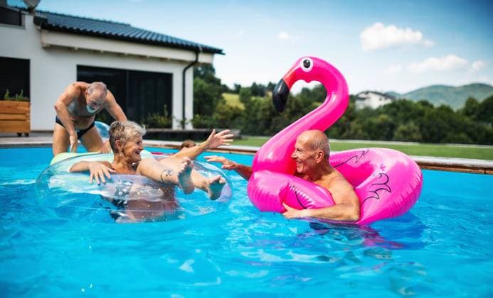 Group of cheerful seniors in swimming pool outdoors in backyard, talking. Group of cheerful seniors in swimming pool outdoors in backyard, talking and having fun. model released Copyright: xx Summer_Splash_Seniors_2020_243