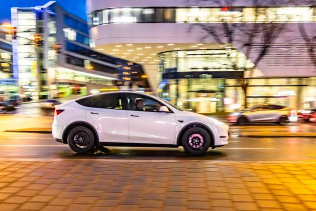 Innerstädtische Straße mit Fahrzeugen, moderne Architektur am Abend. Bewegungsunschärfe. Tesla Model Y. 17.01.2024: Stuttgart, Baden-Württemberg, Deutschland.