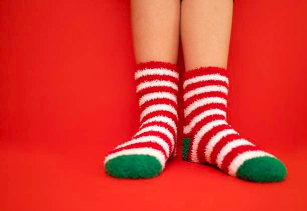 Female feet in fluffy New Year or Christmas warm socks. The colors of the socks are red and white stripes and green heels and tips. Girls legs on a red bright background. Female feet in fluffy New Year or Christmas warm socks. The colors of the socks are red and white stripes and green heels and tips. Girls legs on a red bright background. Celebration holiday concept. Copyright: xZoonar.com DashaxPetrenkox 20824686