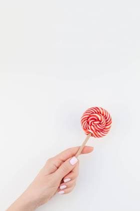 Woman hand with red lollipop Woman hand with pastel manicure polish holding bright red swirling lollipop isolated on white background copy space minimalism style. Template for feminine social media. Fun and celebration concept Copyright: xZoonar.com AnastasiaxZolotnitskayax 20824271
