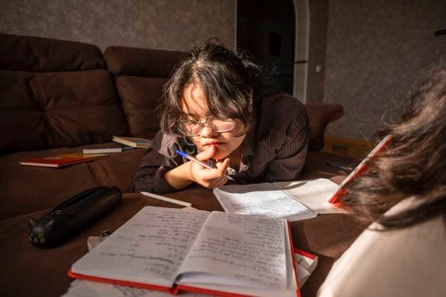 Asian young woman in glasses preparing for exams home on couch Russia, Moscow Oblast, Russia CR_AIAI240121-1334217-01 ,model released, Symbolfoto