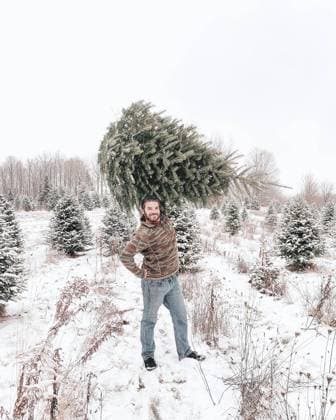 Man holding Christmas Tree Over Head Outside in Snow Dushore, Pennsylvania, United States CR_KPXG231115-1284940-01 ,model released, Symbolfoto