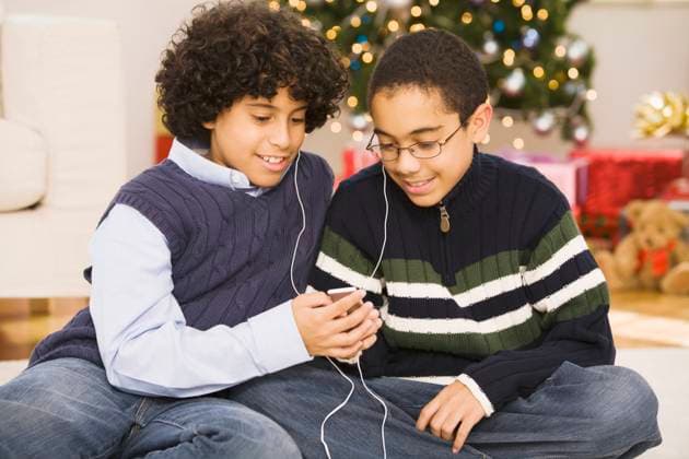 Hispanic brothers sharing mp3 player at Christmas Studio New Jersey, 21.12.2023, model released, TTBB_BLD077651.jpg, 10-11 years, 12-13 years, african ethnicity, bonding, boy, brother, celebration, childhood, christmas, christmas tree, color image, cross-legged, curiosity, domestic life, earbud, enjoying, entertainment, eyeglasses, family, friend, front view, happy, headphone, holding, holding hands, holiday, horizontal, indoors, latin american and hispanic ethnicity, leisure activity, lifestyle, listening, looking down, mp3 player, music, people, photography, pre-adolescent child, sharing, showing, sitting, smiling, technology, three quarter length, together, two people, minority, minorities2, accessory, african, african american, africa Copyright: xJRxCarvey StreetflyxStudiox
