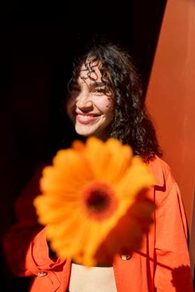 Creative Highlights Symbolbilder Smiling woman with gerbera flower in front of wall model released, Symbolfoto, SECF00003