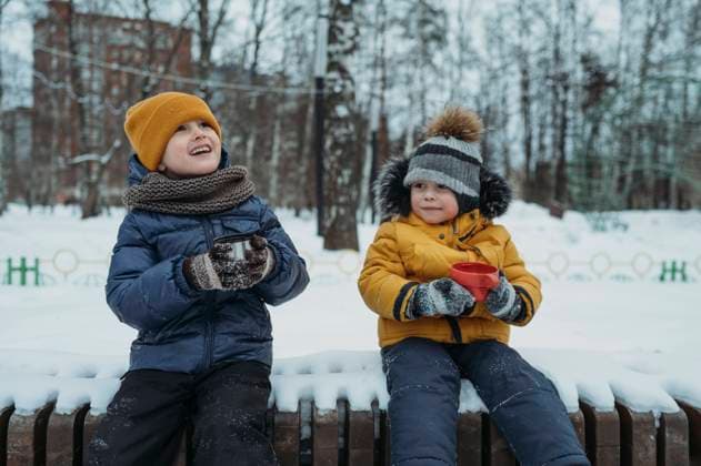 Smiling brothers having tea in winter park model released, Symbolfoto, ANAF02611