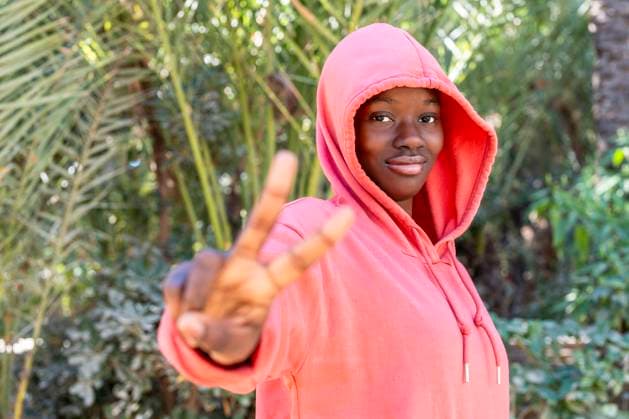 Young woman gesturing peace sign at park model released, Symbolfoto, DLTSF03729