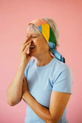Creative Highlights Symbolbilder Woman covering mouth and laughing against pink background model released, Symbolfoto property released, EBSF04351