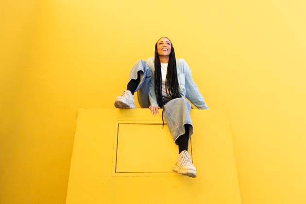 Creative Highlights Symbolbilder Happy young woman sitting near yellow wall model released, Symbolfoto, LMCF00761