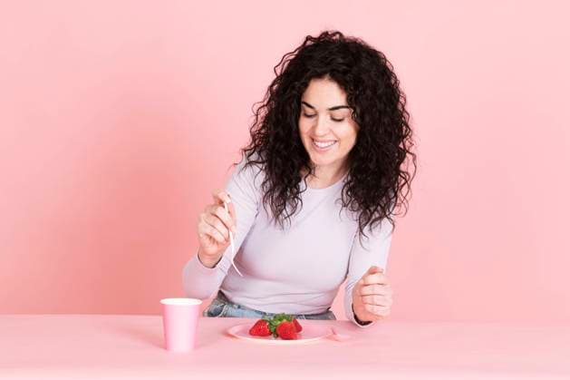 Happy young woman with strawberries and coffee cup at table model released, Symbolfoto, LMCF00801