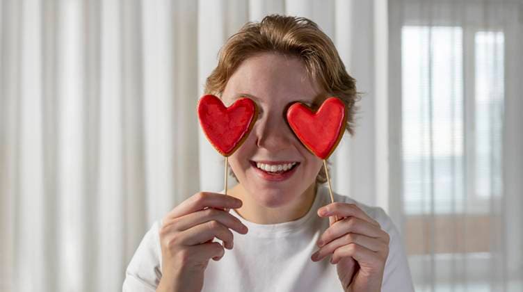 Creative Highlights Symbolbilder Happy woman holding heart shaped cookies over eyes at home model released, Symbolfoto, MBLF00226