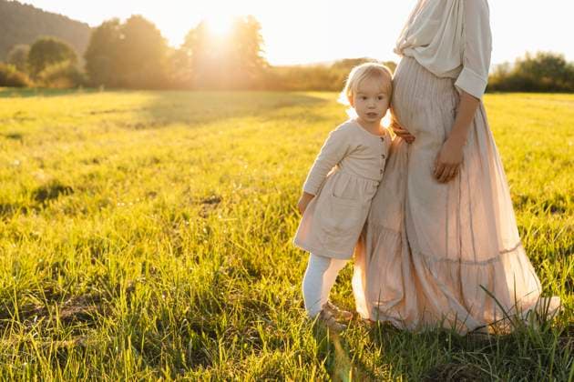 Creative Highlights Symbolbilder Daughter leaning on pregnant mother s stomach in field model released, Symbolfoto, NDEF01514