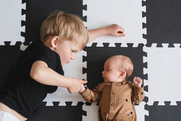 Creative Highlights Symbolbilder Boy holding baby brother s hand on mat model released, Symbolfoto property released, NDEF01521