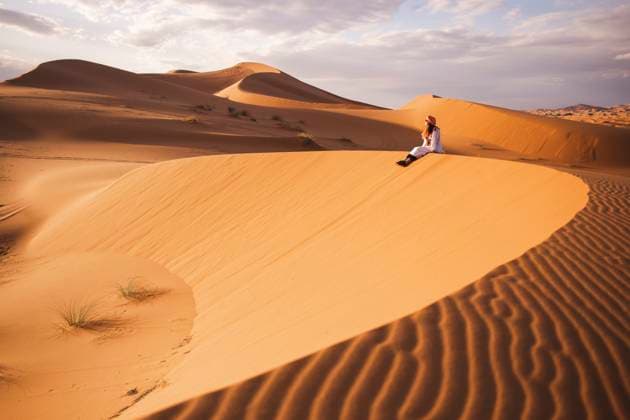 Creative Highlights Symbolbilder Young woman sitting on sand dune at Sahara desert in Morocco, Africa model released, Symbolfoto, PCLF00912