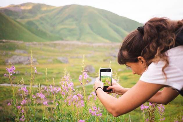 Creative Highlights Symbolbilder Young woman photographing flowering plants through smart phone model released, Symbolfoto property released, PCLF00938