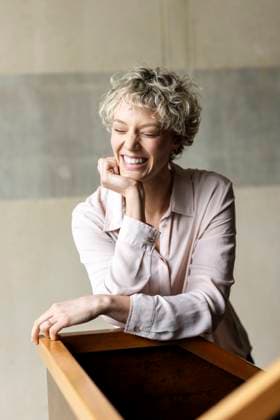 Creative Highlights Symbolbilder Smiling businesswoman with hand on chin in front of wall model released, Symbolfoto property released, PESF04184