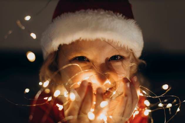 Happy girl wearing Santa hat and holding string lights in hand model released, Symbolfoto, SIF01073