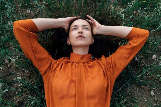 Creative Highlights Symbolbilder Thoughtful woman with head in hands lying in field model released, Symbolfoto, TOF00249