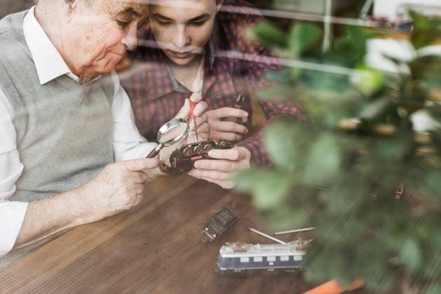 Grandfather repairing miniature train with grandson at home model released, Symbolfoto property released, UUF30861