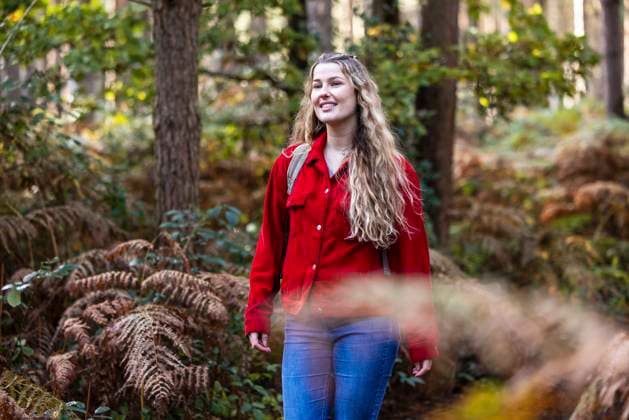 Happy young woman standing near plants in Cannock chase forest model released, Symbolfoto, WPEF08123
