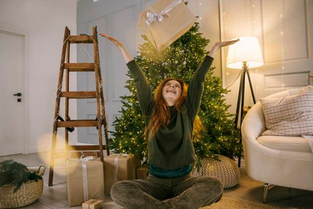 Happy woman throwing gift box near Christmas tree at home model released, Symbolfoto property released, YBF00342