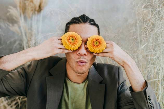 Creative Highlights Symbolbilder Businessman covering eyes with Gerbera daisies in garden model released, Symbolfoto property released, YTF01524