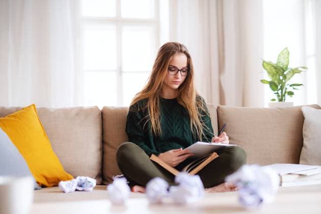 A happy young female student sitting on sofa, studying. A happy young female student sitting on sofa, studying. Copy space. model released Copyright: xx Student_Monika_Polc_2019_449