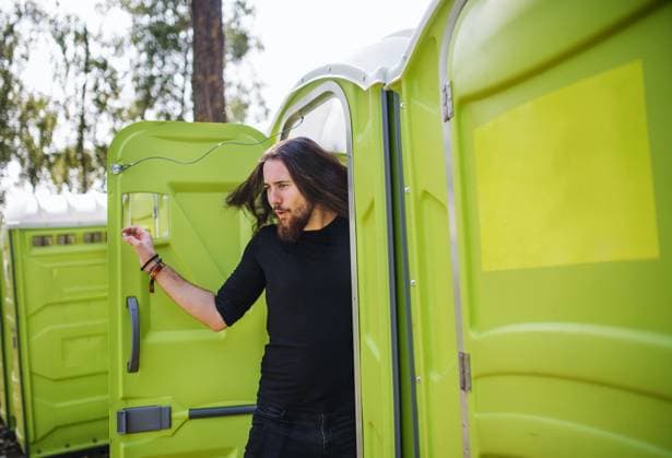 Young man by mobile toilet at summer festival. Young man by mobile toilet at summer festival. Copy space. model released Copyright: xx Uprising_2019_0593