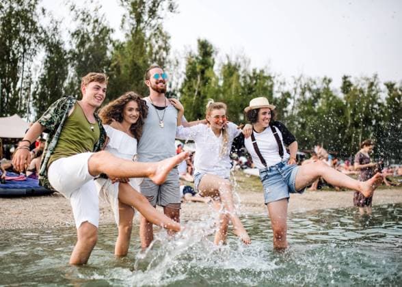 Group of young friends at summer festival, standing in lake. Group of young friends at summer festival, standing in lake and splashing water. model released Copyright: xx Uprising_2019_1552