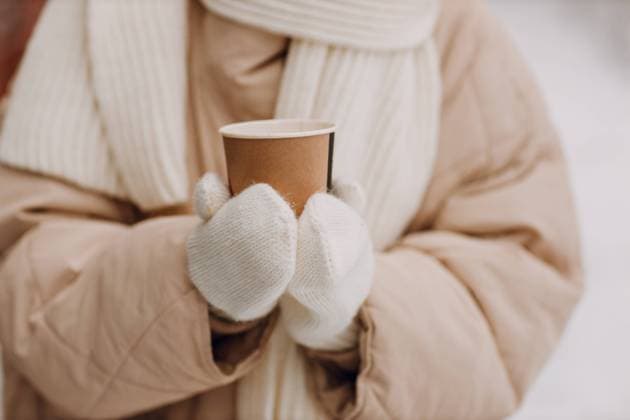 Female hands holding coffee hot drink cup and enjoys winter weather at snowy street. Female hands holding coffee hot drink cup at snowy winter street close up Copyright: xZoonar.com MaksimxChernyshevx 21072281