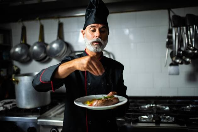 Creative Highlights Symbolbilder Chef garnishing dish in professional kitchen Abbadia Cerreto, Lombardy, Italy CR_SUZV240117-1330843-01 ,model released, Symbolfoto
