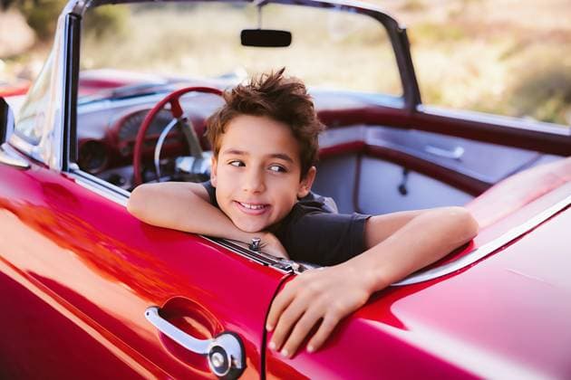 Creative Highlights Symbolbilder Young boy sitting in red classic car smiling United States, California, San Diego R_CHDO240118-1303590-01 ,model released, Symbolfoto