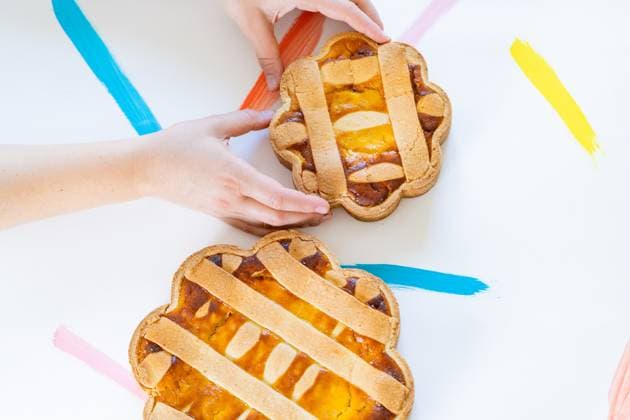 Cropped unrecognizable hands arranging Italian Easter pastiera napoletana pastries on a white surface with colorful brushstrokes. Model Released VictorCuenca_ID18923_563580_012 Copyright: xVictorxCuencax