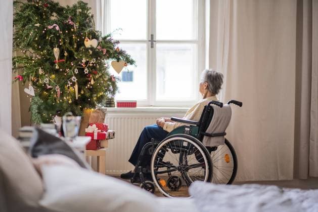A rear view of a senior woman in wheelchair at home at Christmas time. A rear view of a lonely senior woman in wheelchair at home at Christmas time, looking out of a window. model released Copyright: xx Sen_Health 3_2018_113
